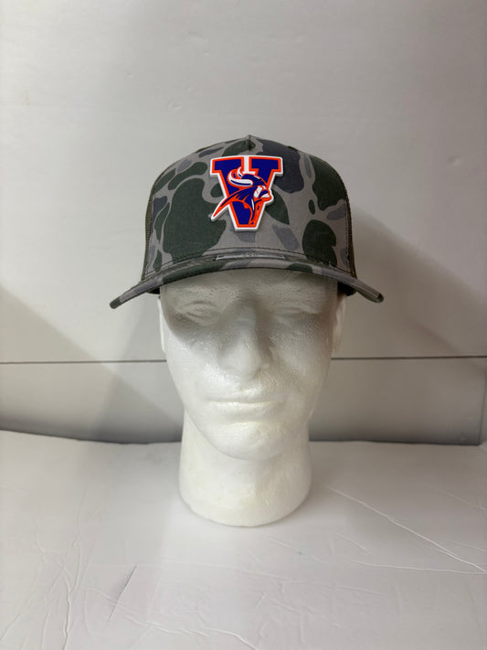 Camouflage-patterned Missouri valley college cap with a logo on a mannequin head against a white tiled wall.