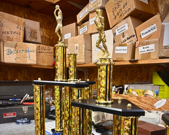 Gold and black trophies on a counter with cardboard boxes in the background